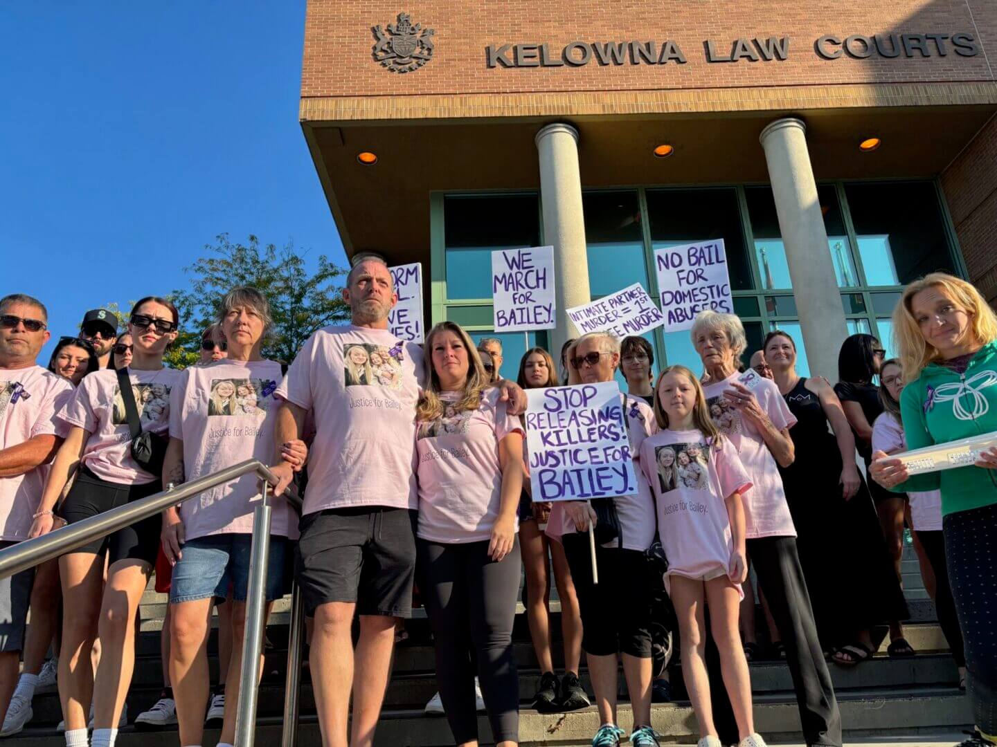 Group of protesters holding signs outside a courthouse.