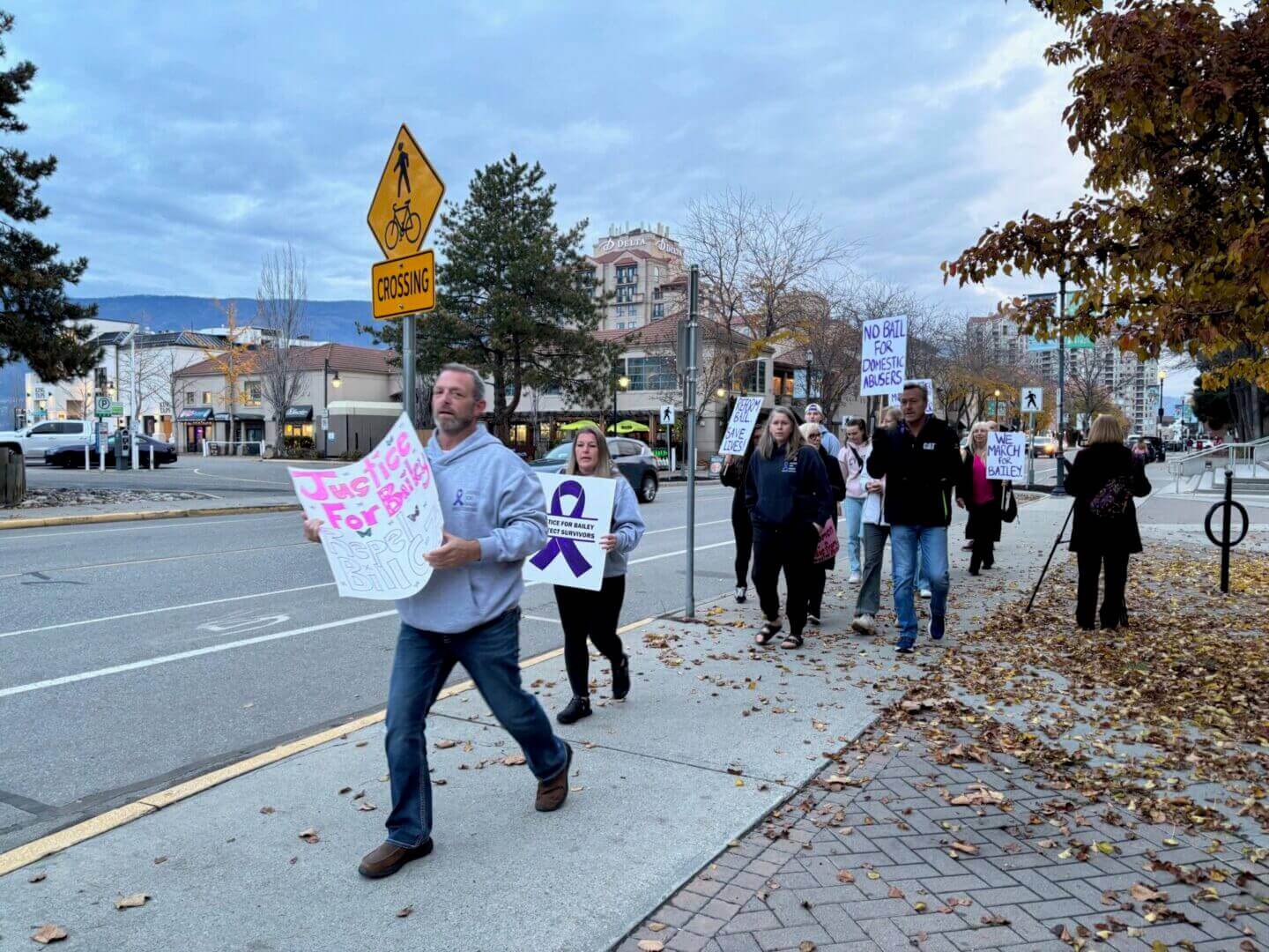 People march on a sidewalk holding signs in a peaceful protest.